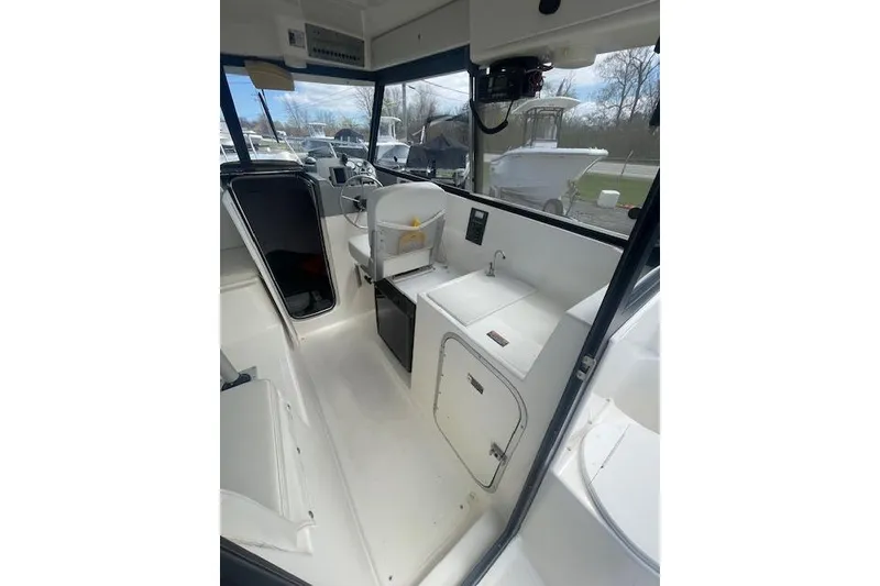 Slide: The Image of 2006 Trophy 2359 Hardtop boat interior with helm, seating, and compact kitchenette. - 11