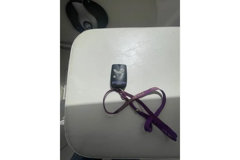Slide: The Image of Remote key fob with purple lanyard on white surface, 2006 Trophy 2359 Hardtop. - 12