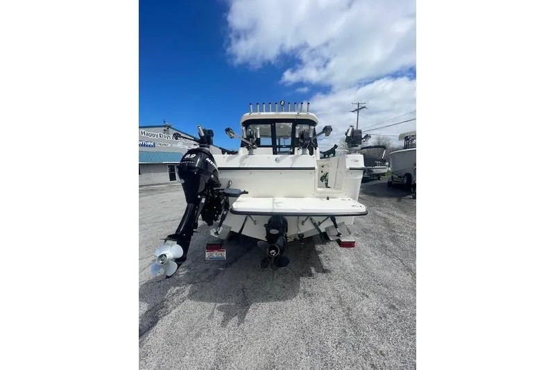 Slide: The Image of 2006 Trophy 2359 Hardtop boat, rear view, parked outdoors under a blue sky. - 19