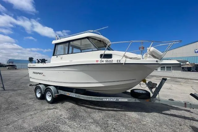 Slide: The Image of 2006 Trophy 2359 Hardtop boat on trailer, parked outdoors under a clear blue sky. - 4