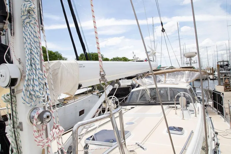 Slide: The Image of Sailboat deck view of 2015 Outbound 46, featuring rigging and marina backdrop. - 10