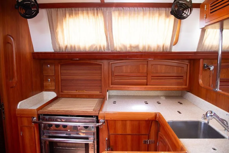 Slide: The Image of Luxurious wooden kitchen interior of a 2015 Outbound 46 yacht, featuring modern appliances. - 36