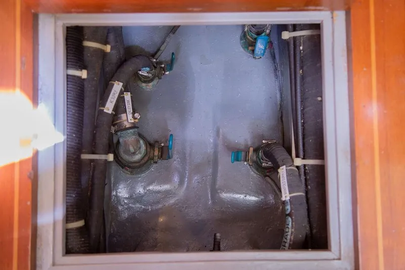 Slide: The Image of Engine compartment of a 2015 Outbound 46 yacht, showing hoses and valves. - 57