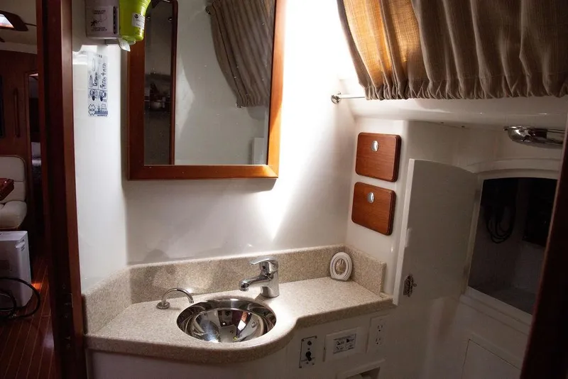 Slide: The Image of Compact bathroom in 2015 Outbound 46 yacht with sink, mirror, and storage cabinets. - 60