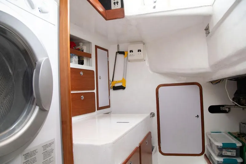Slide: The Image of Laundry area inside 2015 Outbound 46 yacht, featuring washer, storage cabinets, and tools. - 67