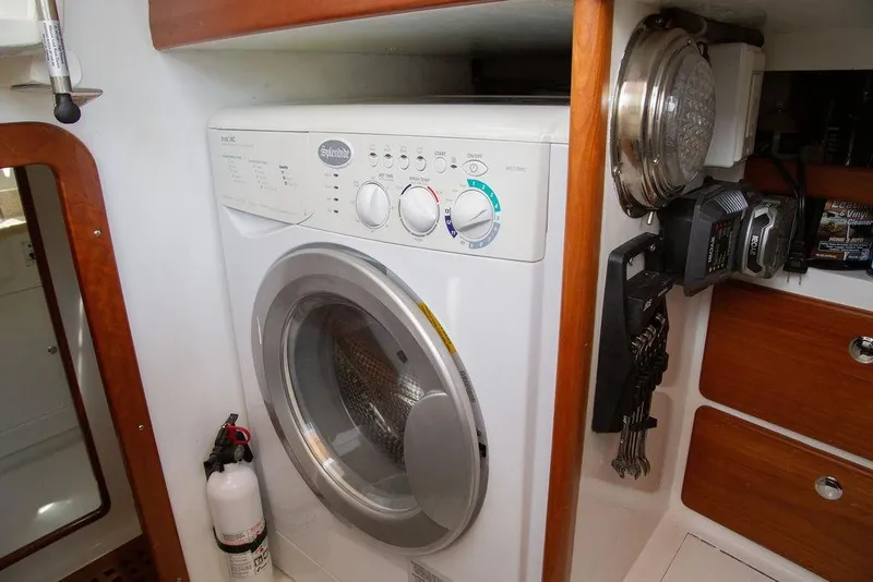Slide: The Image of Laundry area inside 2015 Outbound 46 yacht with washer and wooden cabinetry. - 68
