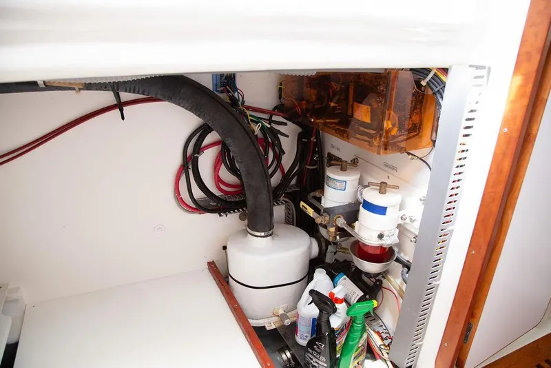 Slide: The Image of Engine compartment of a 2015 Outbound 46 yacht, featuring hoses, filters, and cleaning supplies. - 71