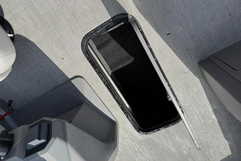 Slide: The Image of Open storage compartment on 2025 Qwest Splash Pad E-Class boat deck. - 2