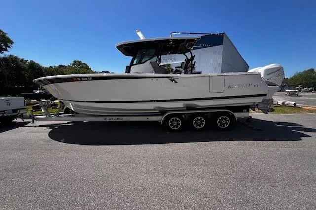 The Image of 2020 Blackfin 332 CC boat on trailer, parked outdoors under clear blue sky. - 0