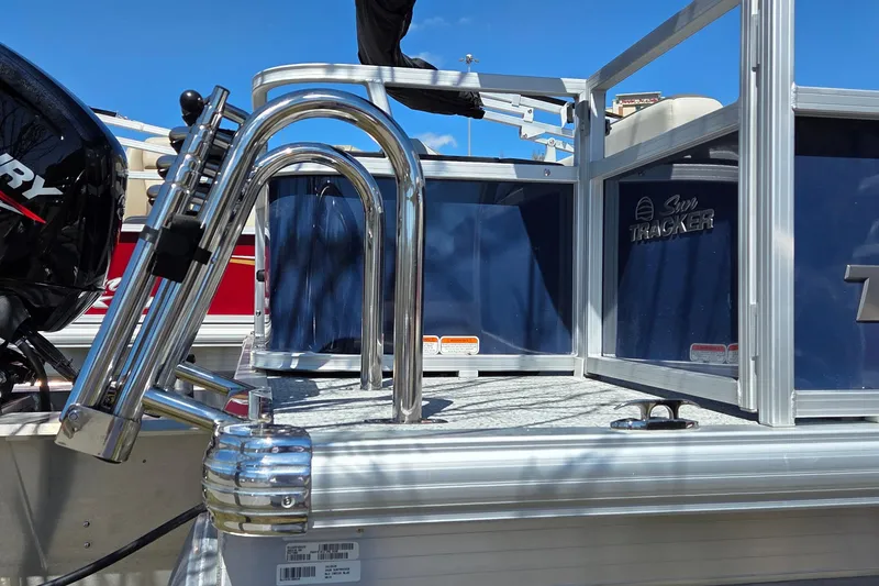 Slide: The Image of 2026 Sun Tracker Bass Buggy 18 DLX pontoon boat with Mercury engine, docked outdoors. - 2