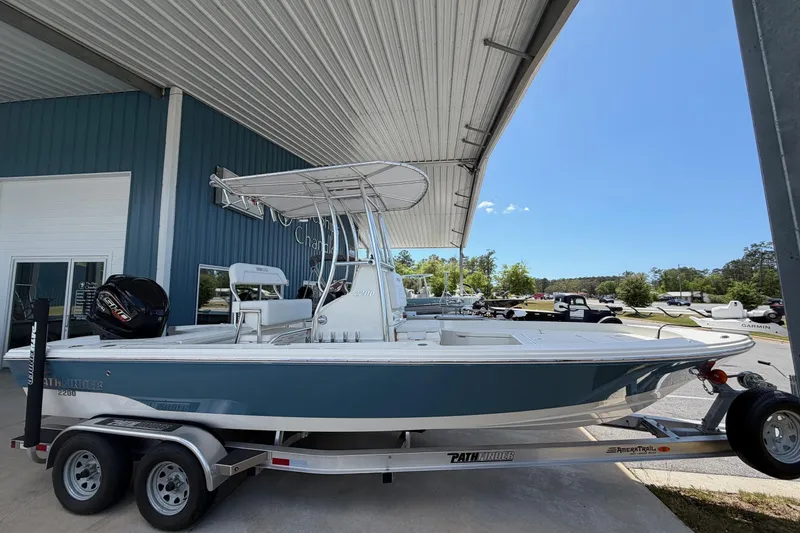 The Image of 2025 Pathfinder 2200 TRS boat on trailer, parked under a metal canopy. - 0
