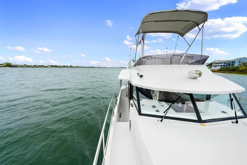 Slide: The Image of 2018 Beneteau Swift Trawler 30 cruising on calm waters under a clear blue sky. - 10