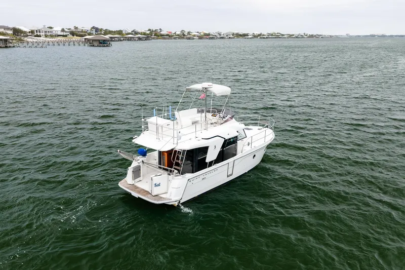 Slide: The Image of 2018 Beneteau Swift Trawler 30 cruising on open water near coastal homes. - 17