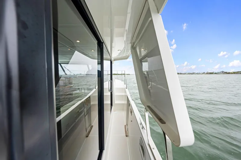 Slide: The Image of 2018 Beneteau Swift Trawler 30 side deck view with open window, overlooking calm waters. - 23