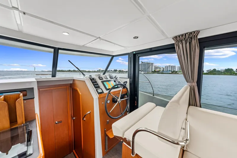 Slide: The Image of Interior view of 2018 Beneteau Swift Trawler 30 helm with scenic waterway backdrop. - 29