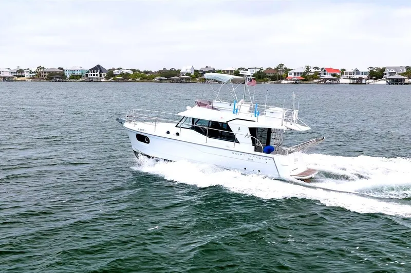 Slide: The Image of 2018 Beneteau Swift Trawler 30 cruising on open water near coastal homes. - 3