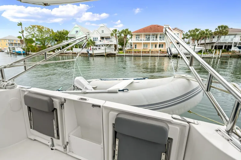 Slide: The Image of 2018 Beneteau Swift Trawler 30 with dinghy, docked near waterfront homes. - 31