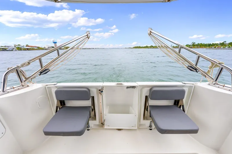 Slide: The Image of 2018 Beneteau Swift Trawler 30 rear deck with foldable seats, overlooking serene waters. - 32