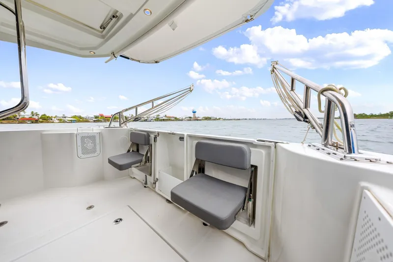 Slide: The Image of 2018 Beneteau Swift Trawler 30 deck with seating, overlooking serene waters and blue sky. - 35