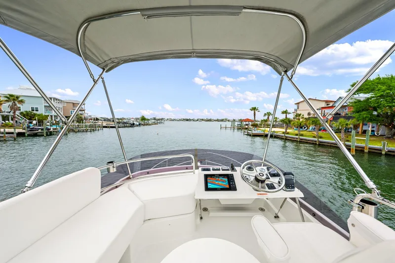 Slide: The Image of 2018 Beneteau Swift Trawler 30 helm view, cruising through a scenic waterfront neighborhood. - 41