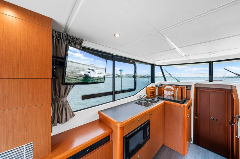 Slide: The Image of 2018 Beneteau Swift Trawler 30 interior with kitchen, TV, and ocean view. - 45