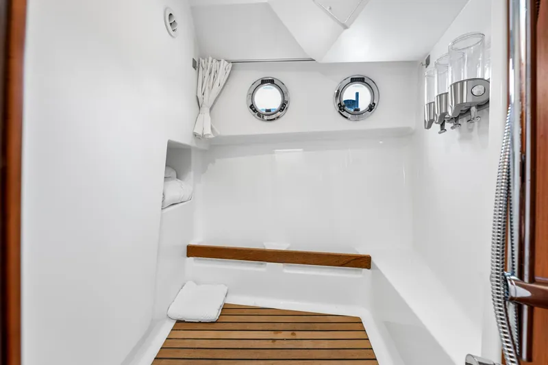 Slide: The Image of Interior of 2018 Beneteau Swift Trawler 30 bathroom with portholes and wooden accents. - 66