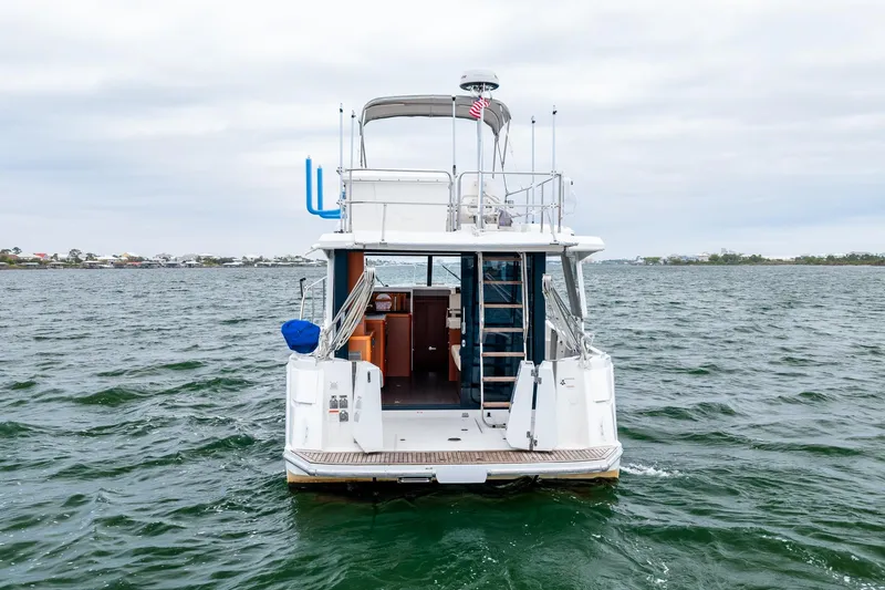 Slide: The Image of 2018 Beneteau Swift Trawler 30 on open water, rear view with visible deck and cabin. - 75