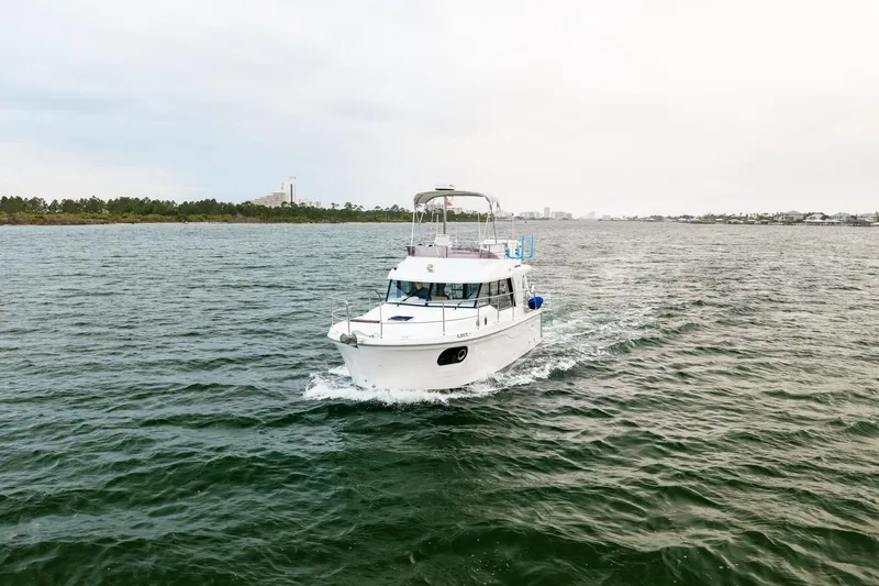 Slide: The Image of 2018 Beneteau Swift Trawler 30 cruising on open water, distant shoreline visible. - 76