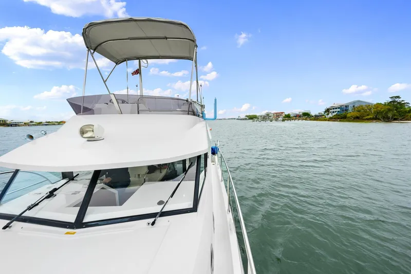 Slide: The Image of 2018 Beneteau Swift Trawler 30 cruising on a scenic waterway under a clear blue sky. - 9