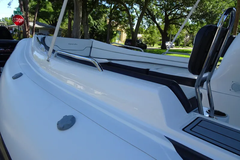 Slide: The Image of 2022 Walker Bay Generation 525 boat, sleek white design, parked outdoors with lush greenery. - 11