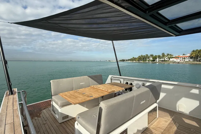 Slide: The Image of 2019 Fjord 40' Open yacht with shaded deck, wooden table, and scenic water view. - 46