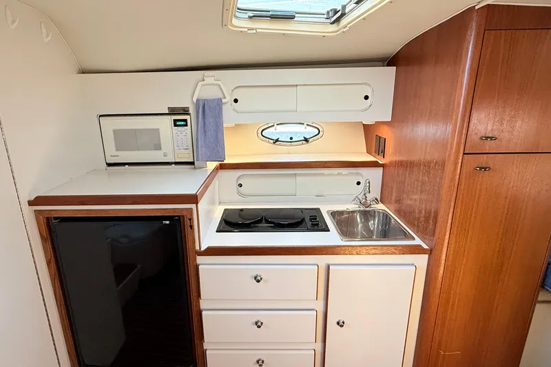 Slide: The Image of Compact kitchen in a 1997 Tiara 3100 Open Express boat, featuring stove, sink, and microwave. - 20