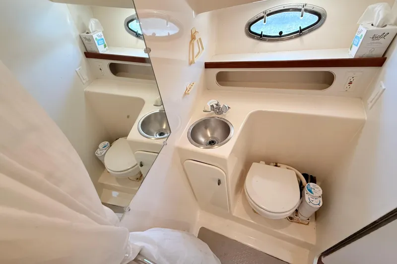 Slide: The Image of 1997 Tiara 3100 Open Express boat bathroom with sink, toilet, and porthole window. - 23
