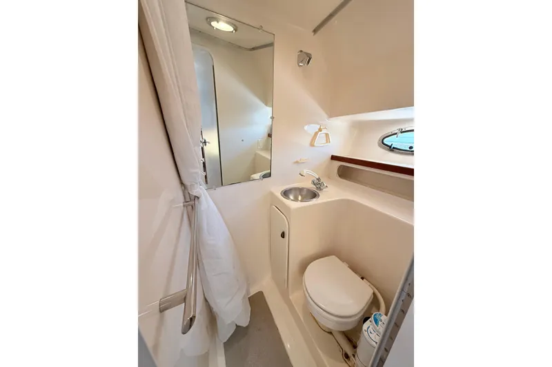 Slide: The Image of Compact bathroom in 1997 Tiara 3100 Open Express yacht, featuring sink, toilet, and mirror. - 24