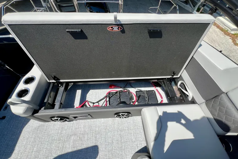 Slide: The Image of Open storage compartment on 2026 Harris Sunliner 210 boat, featuring cup holders and speakers. - 19