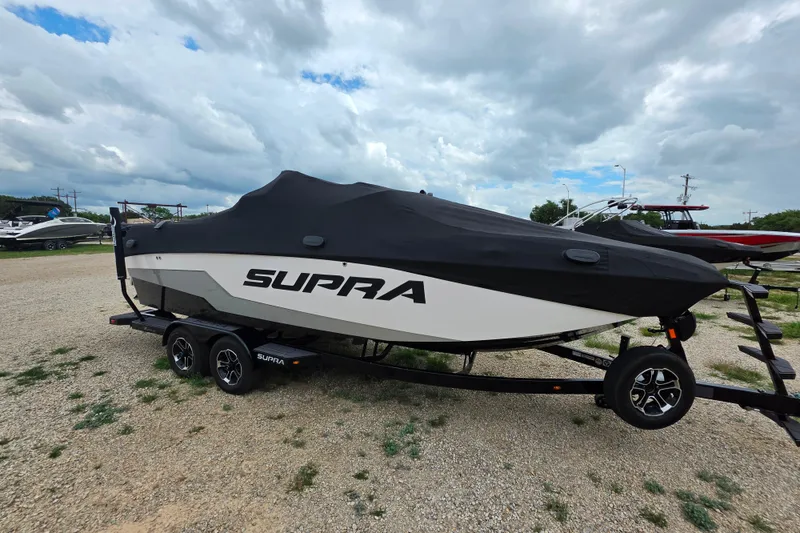 Slide: The Image of 2023 Supra SL 450 boat covered on trailer under cloudy sky. - 38