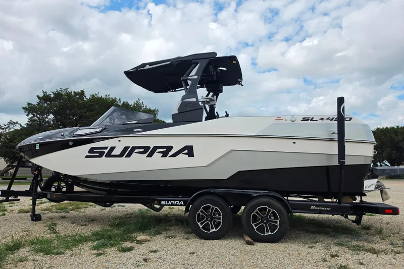 Slide: The Image of 2023 Supra SL 450 boat on trailer, parked outdoors under a cloudy sky. - 6