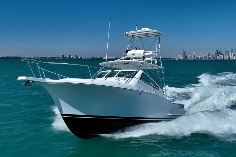Slide: The Image of 2004 Luhrs Tournament 320 Open yacht cruising on blue ocean with city skyline backdrop. - 2
