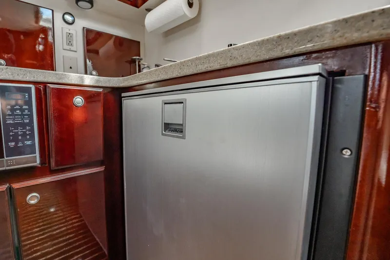 Slide: The Image of 2004 Luhrs Tournament 320 Open yacht kitchen with stainless steel fridge and wooden cabinetry. - 39