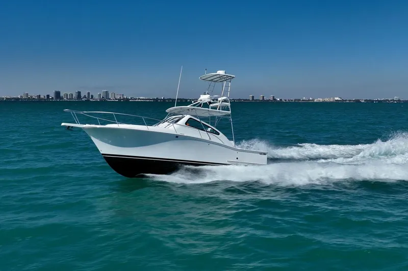 Slide: The Image of 2004 Luhrs Tournament 320 Open cruising on blue ocean with city skyline backdrop. - 56