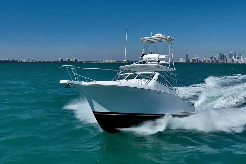 Slide: The Image of 2004 Luhrs Tournament 320 Open cruising on turquoise waters with city skyline backdrop. - 57