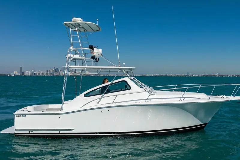 Slide: The Image of 2004 Luhrs Tournament 320 Open boat cruising on blue ocean with city skyline backdrop. - 6