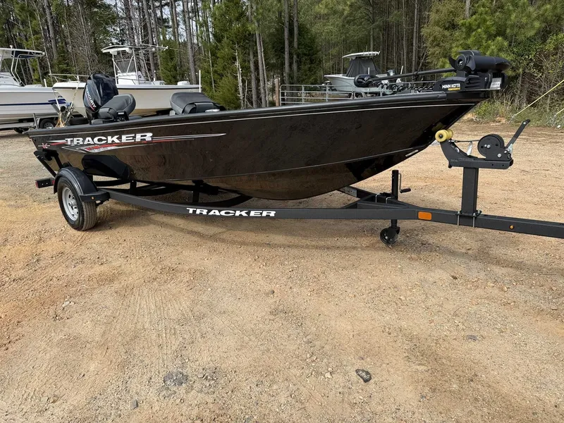 Slide: The Image of 2025 Tracker Super Guide V16 Tiller boat with trailer outdoors. - 6