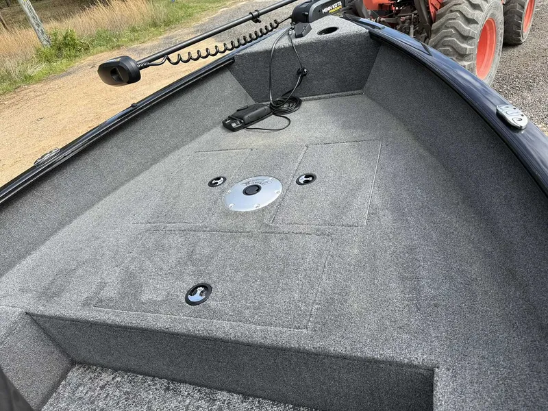 Slide: The Image of 2025 Tracker Super Guide V16 Tiller boat with gray carpeted deck. - 9