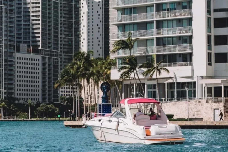 Slide: The Image of 2001 Sea Ray 360 Express Cruiser docked near modern cityscape and palm trees. - 13