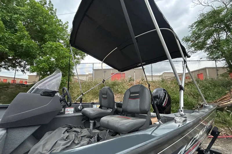 Slide: The Image of 2021 Tracker Pro Guide V-16 SC boat with canopy and seating, parked outdoors. - 11