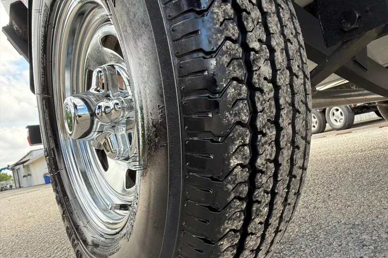 Slide: The Image of Close-up of a 2021 Tracker Pro Guide V-16 SC trailer tire on asphalt. - 16