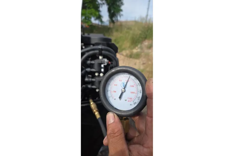 Slide: The Image of Hand holding pressure gauge near Tracker Pro Guide V-16 SC engine, 2021 model. - 46