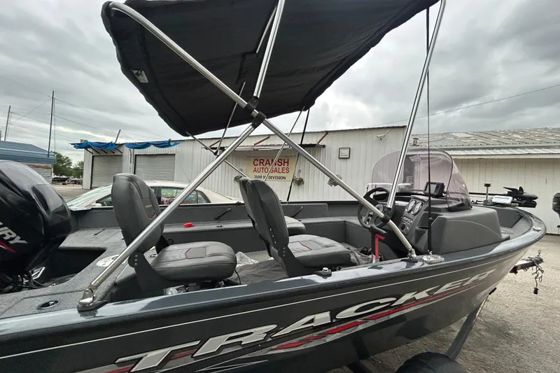 Slide: The Image of 2021 Tracker Pro Guide V-16 SC boat with canopy, parked near auto sales building. - 9