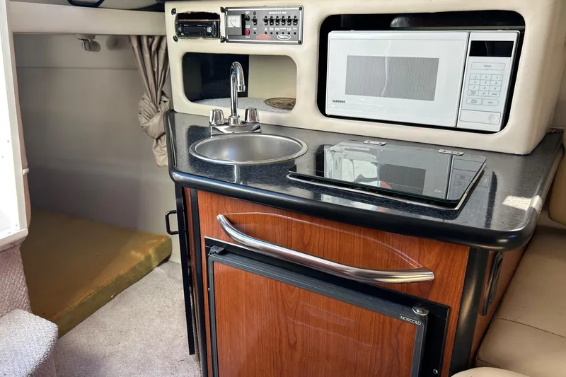 Slide: The Image of 2001 Chaparral Signature 240 boat interior with kitchenette, featuring sink, microwave, and stove. - 30